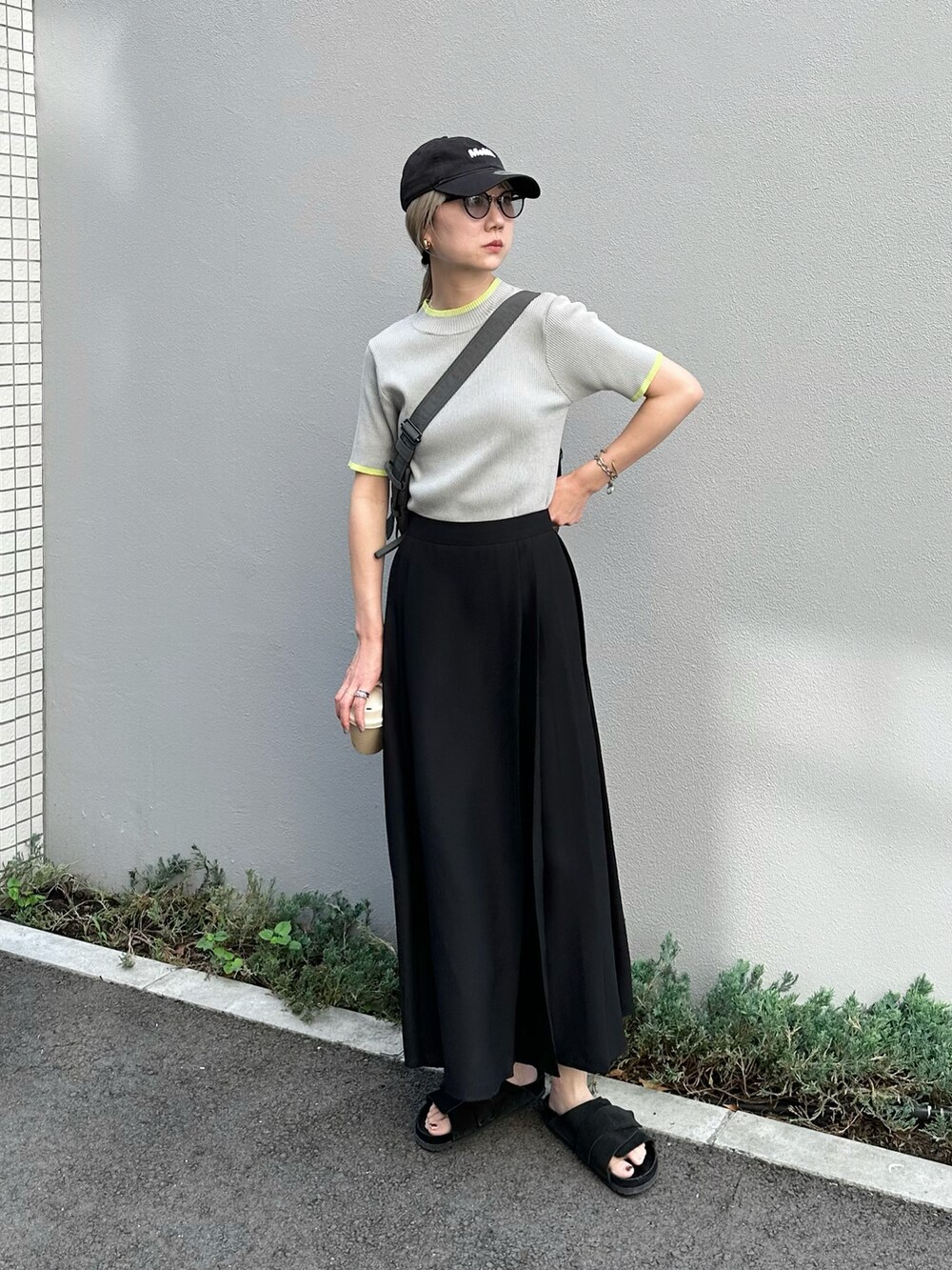グレー系のニット/セーター、ブラック系のスカート、ブラック系のサンダルを着用したレディースの夏コーディネートの4枚目の写真