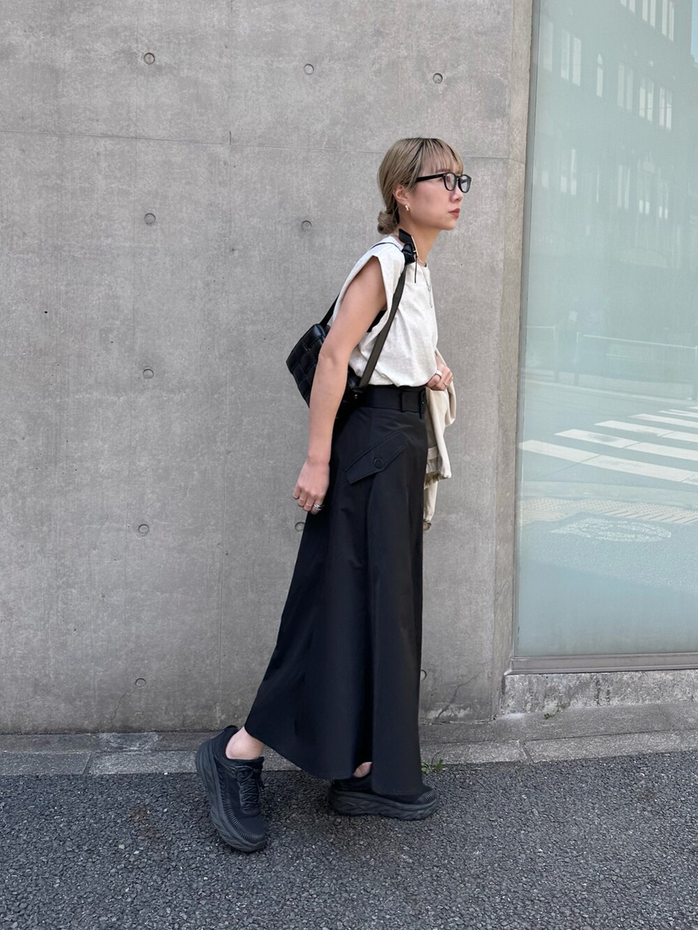 ブラック系のスカート、ホワイト系のミリタリージャケット、ベージュ系のタンクトップを着用したレディースの春コーディネートの3枚目の写真