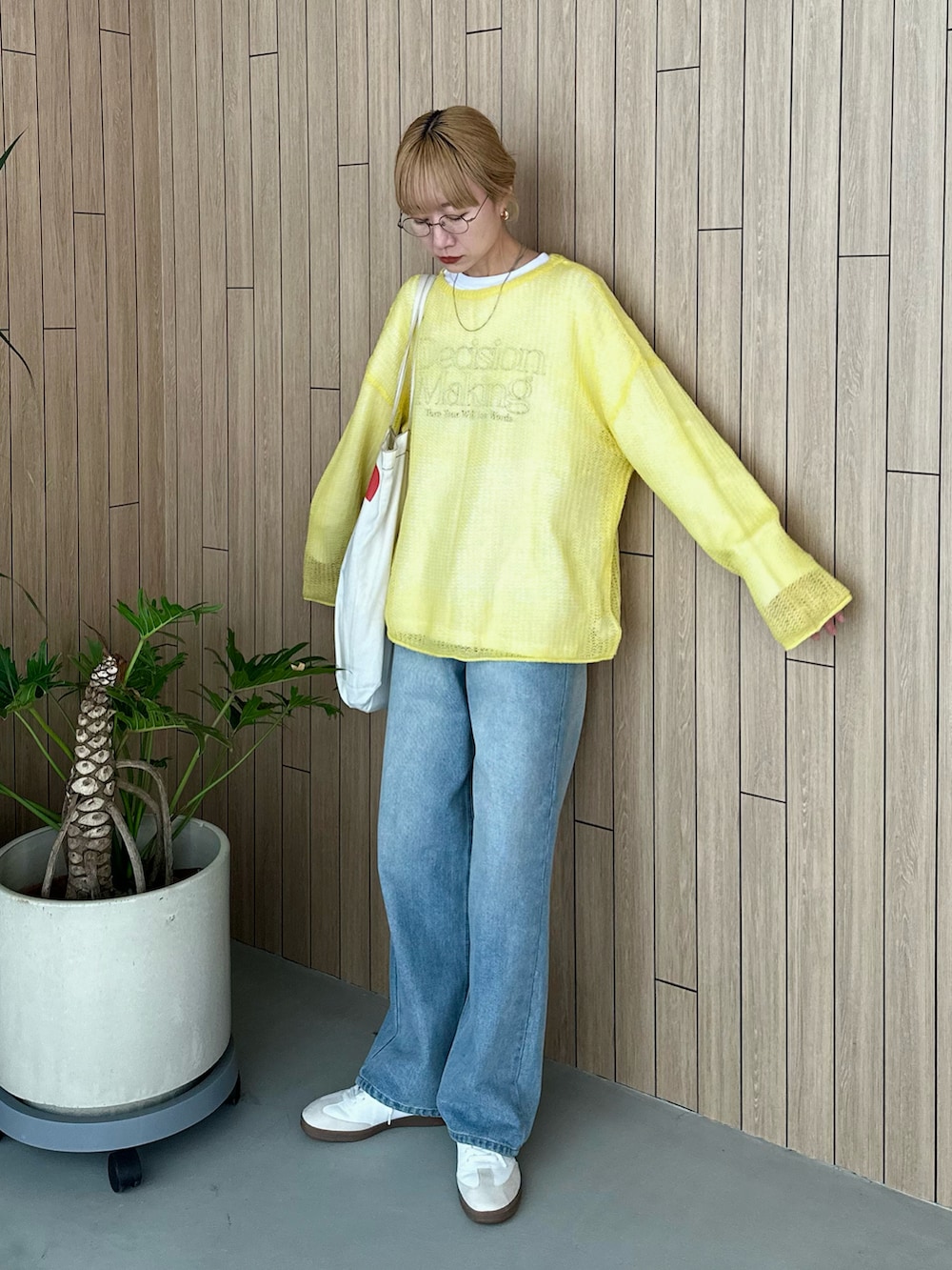 ホワイト系のスウェット、イエロー系のニット/セーター、ブルー系のデニムパンツを着用したレディースの春コーディネートの3枚目の写真