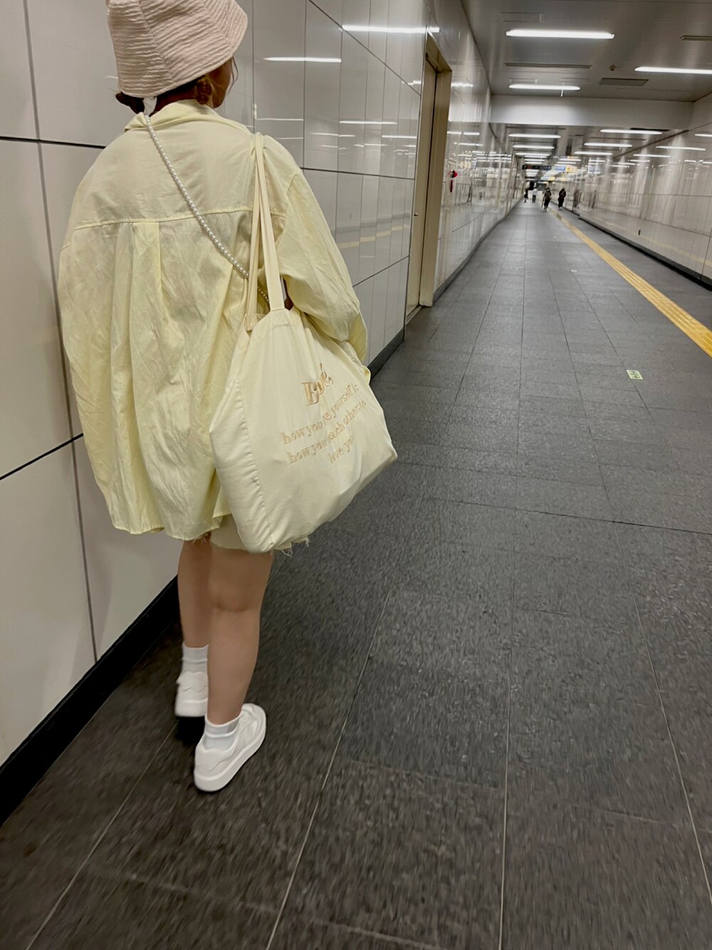 イエロー系のシャツ/ブラウス、ベージュ系のトートバッグを着用したレディースの夏コーディネートの2枚目の写真