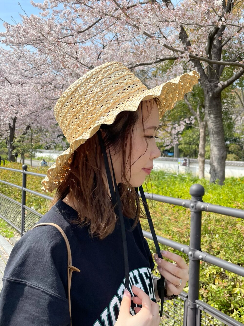 グリーン系のショルダーバッグ、オレンジ系のスカート、ブラック系のTシャツ/カットソーを着用したレディースの春コーディネートの3枚目の写真