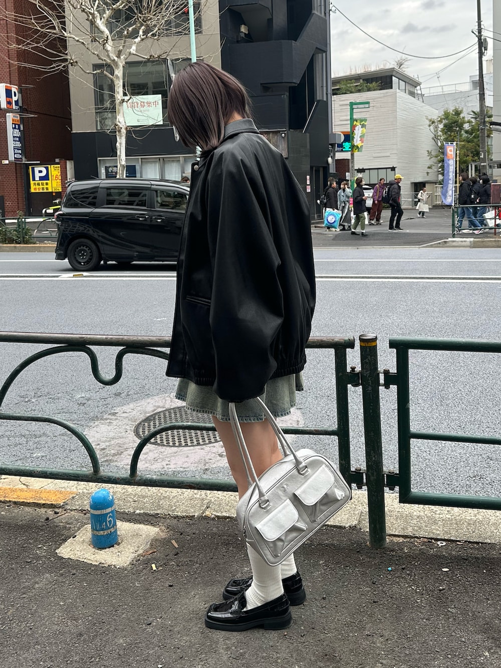 ブラック系のスウェット、ブラック系のブルゾン、ブルー系のデニムスカートを着用したレディースの冬コーディネートの2枚目の写真