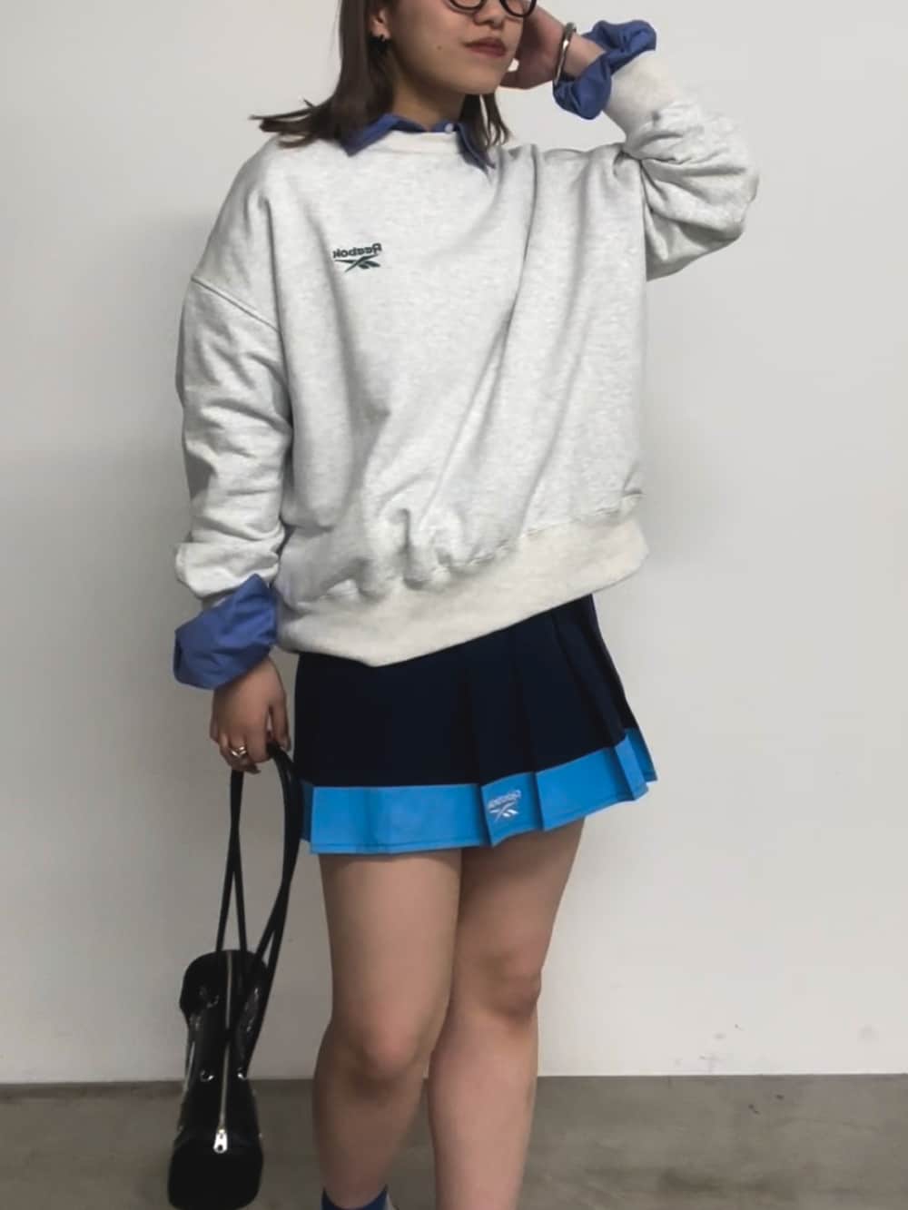 グレー系のトップス、ブルー系のシャツ/ブラウス、ブラック系のバッグを着用したレディースの春コーディネートの3枚目の写真