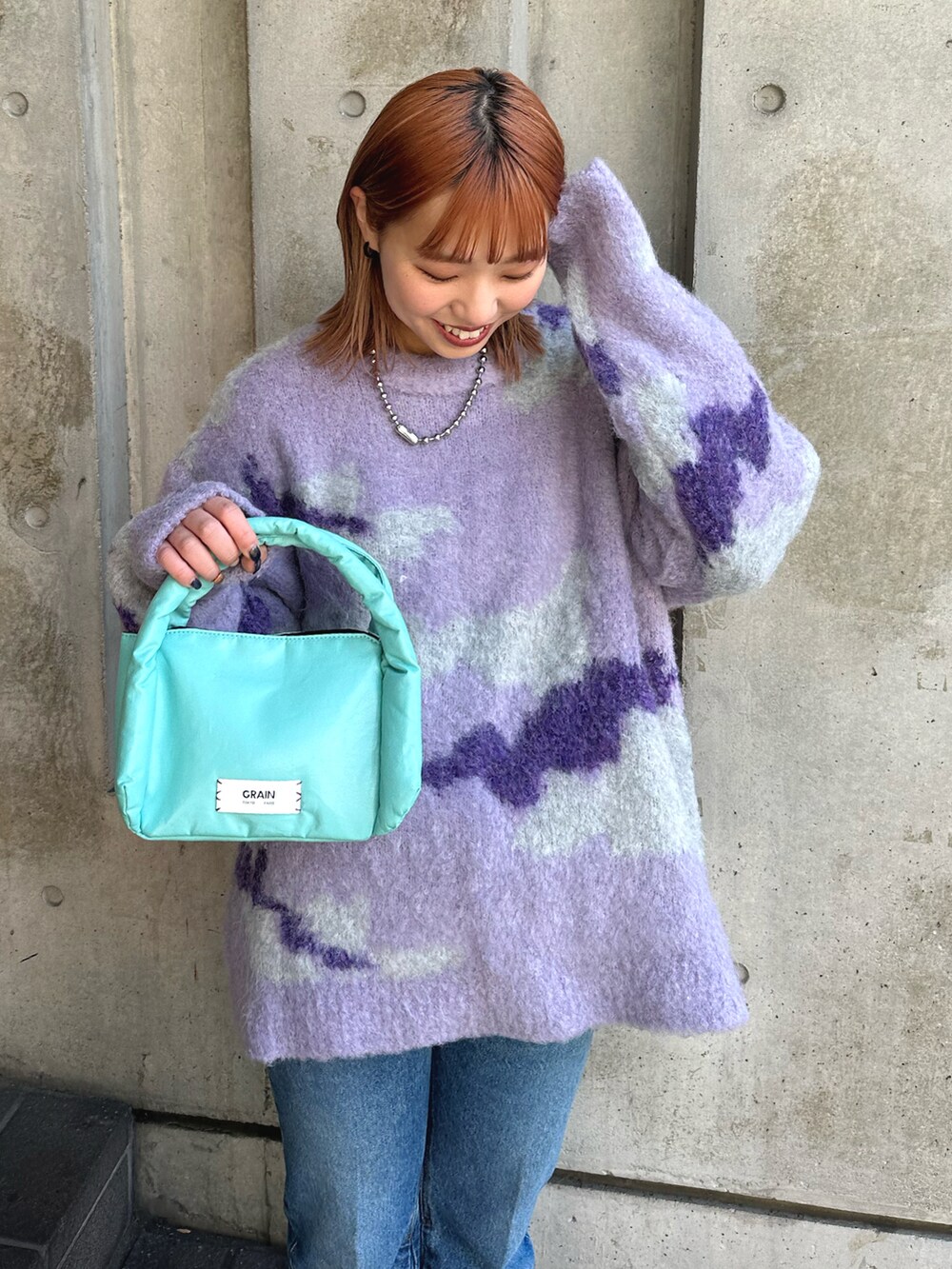 パープル系のニット/セーター、ブルー系のデニムパンツ、ブルー系のハンドバッグを着用したレディースの冬コーディネートの3枚目の写真