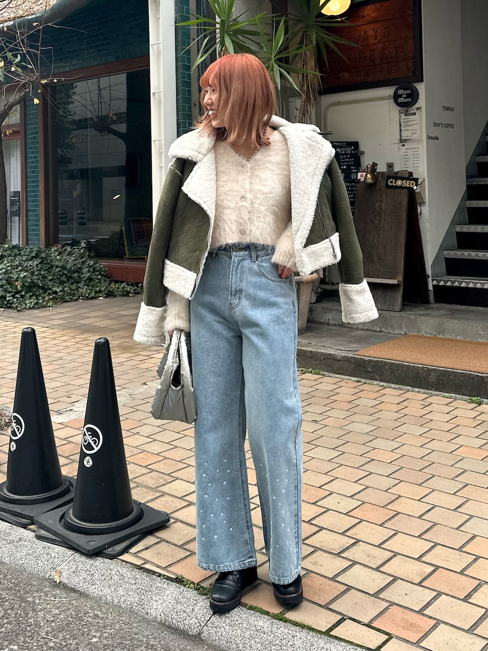 ブルー系のデニムパンツ、ホワイト系のムートンコート、ホワイト系のニット/セーターを着用したレディースの冬コーディネートの2枚目の写真