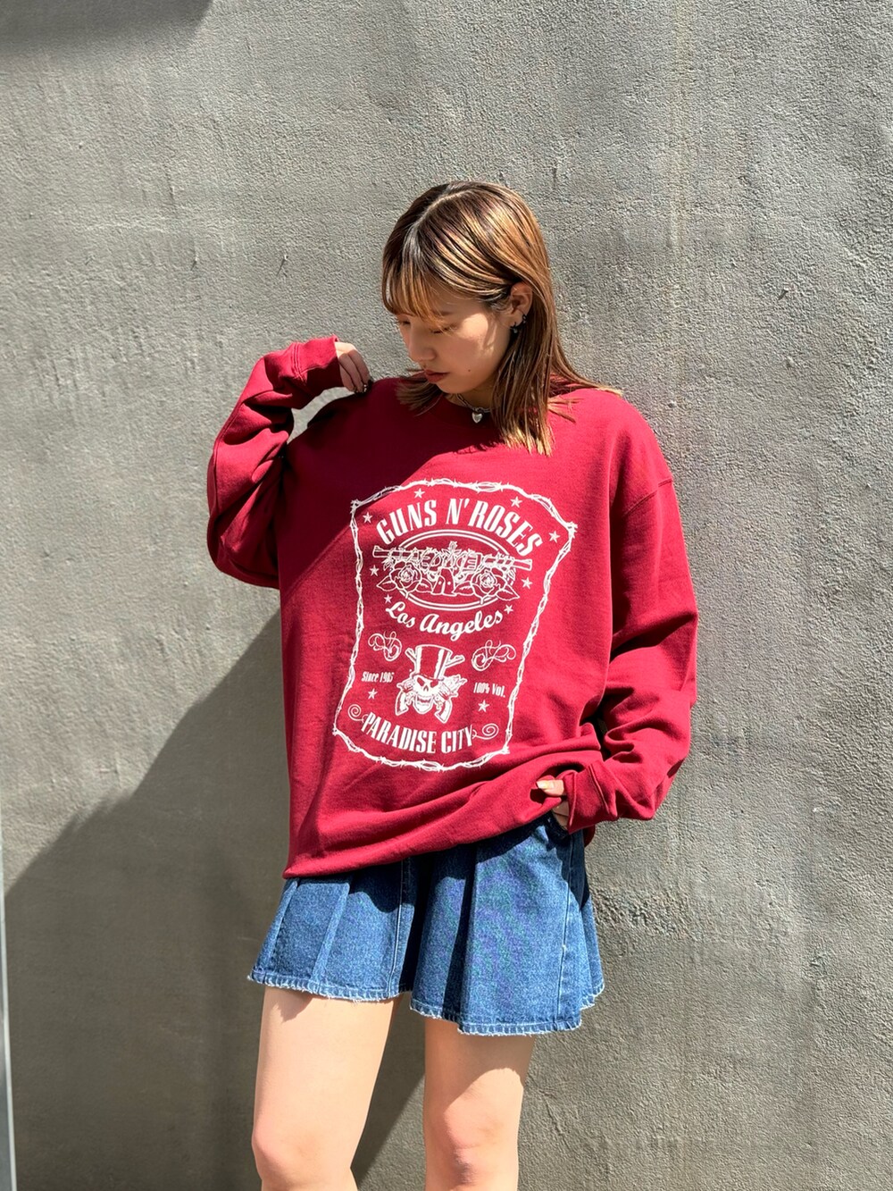 レッド系のスウェット、ブルー系のデニムスカートを着用したレディースの春コーディネートの2枚目の写真