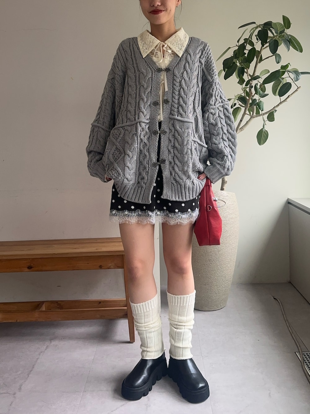 グレー系のカーディガン/ボレロ、ホワイト系のシャツ/ブラウス、ブラック系のスカートを着用したレディースの冬コーディネートの2枚目の写真