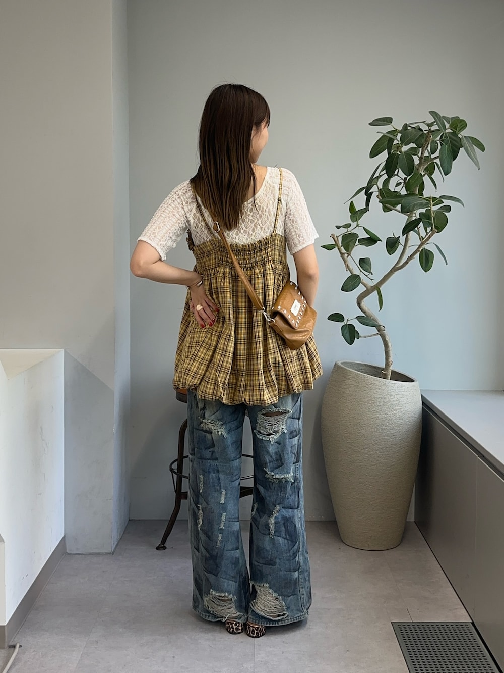 イエロー系のキャミソール、ブラウン系のショルダーバッグ、ブルー系のデニムパンツを着用したレディースの夏コーディネートの2枚目の写真