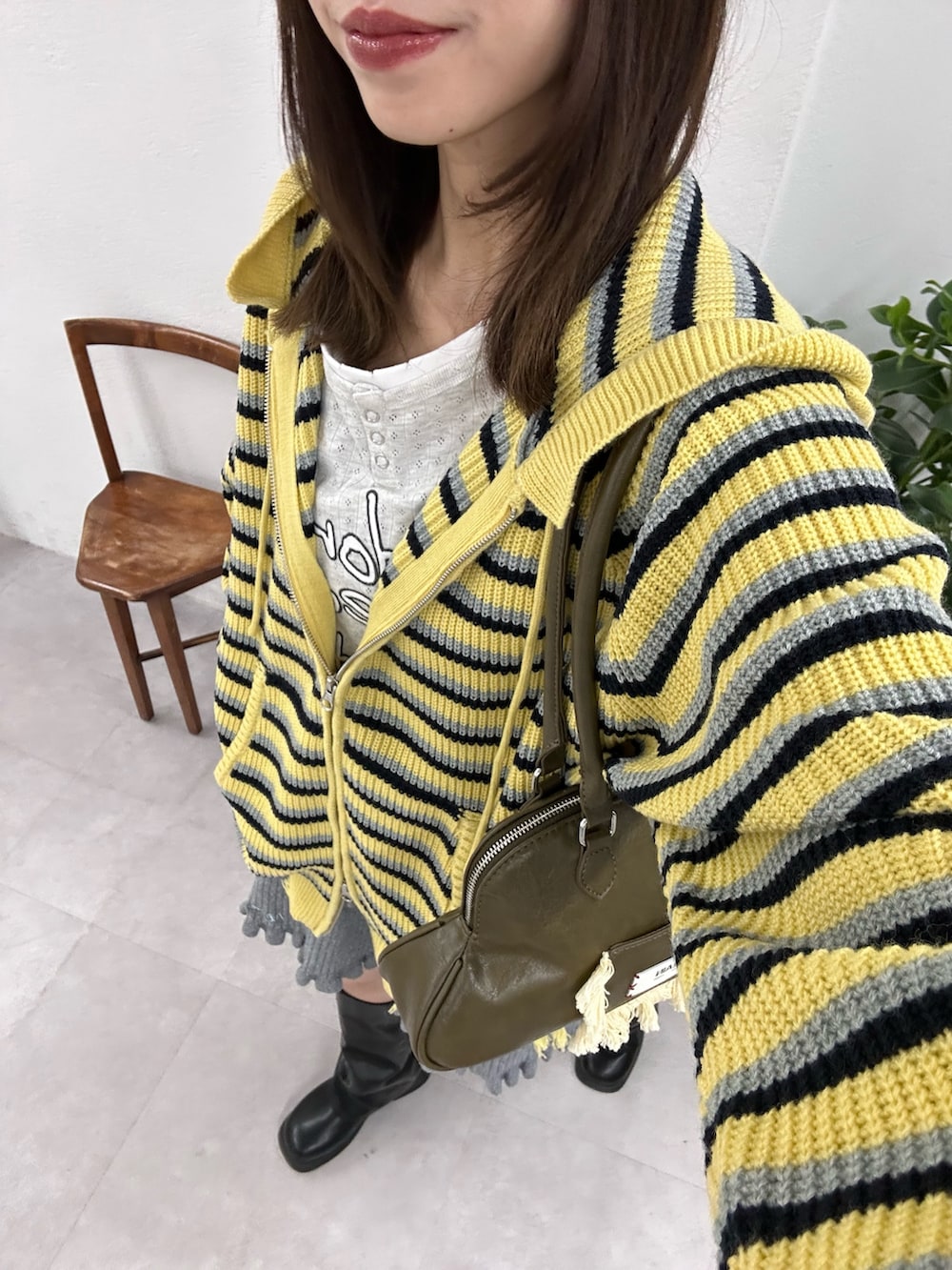 イエロー系のパーカー、ブラック系のブーツを着用したレディースの冬コーディネートの2枚目の写真