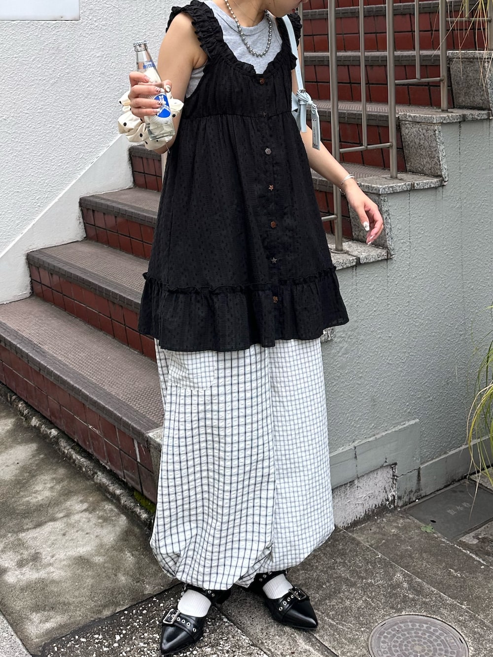 ブラック系のチュニックを着用したレディースの夏コーディネートの2枚目の写真
