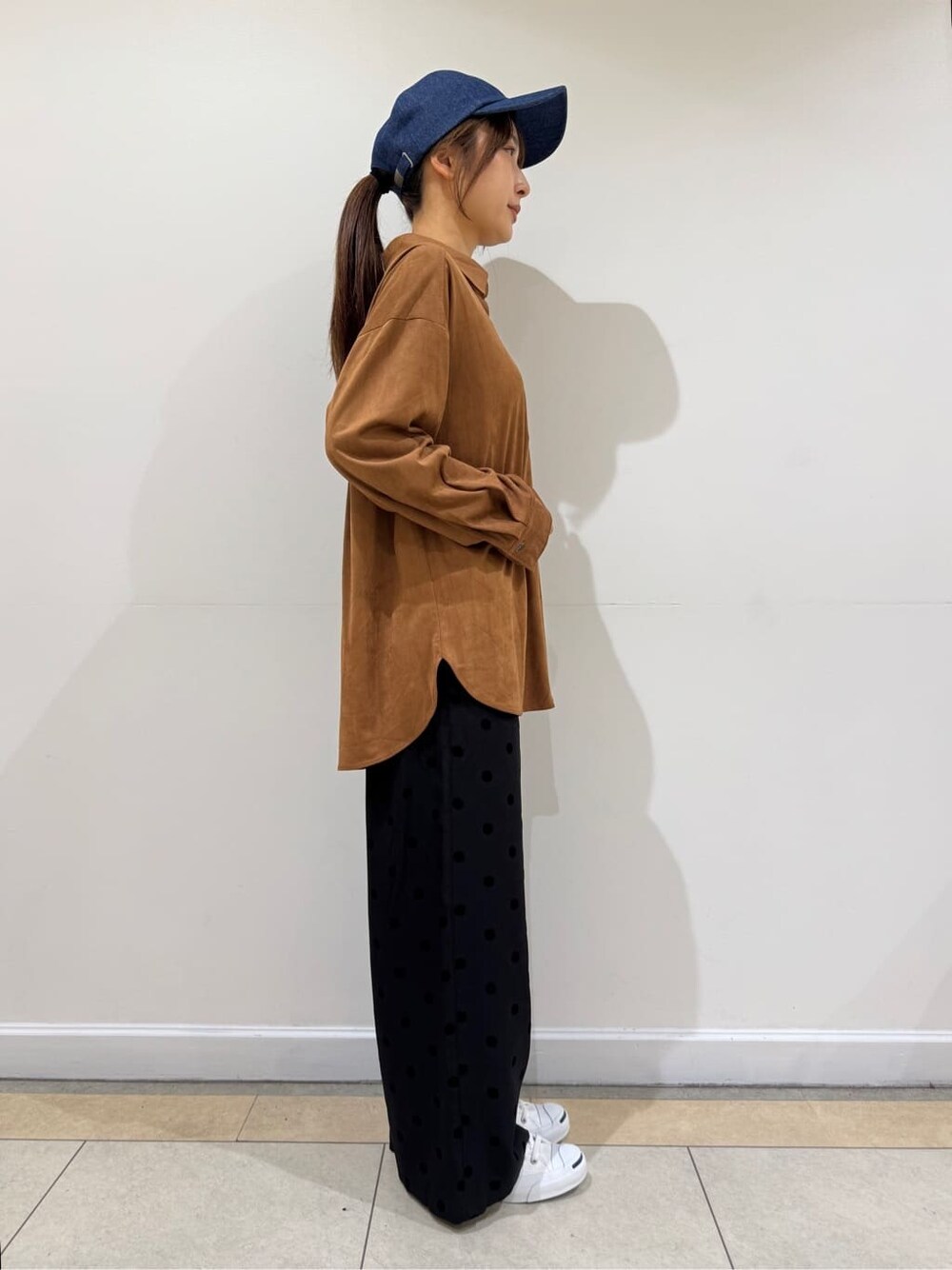 イエロー系のシャツ/ブラウス、ブラック系のその他パンツ、ブルー系のキャップを着用したレディースの秋コーディネートの3枚目の写真