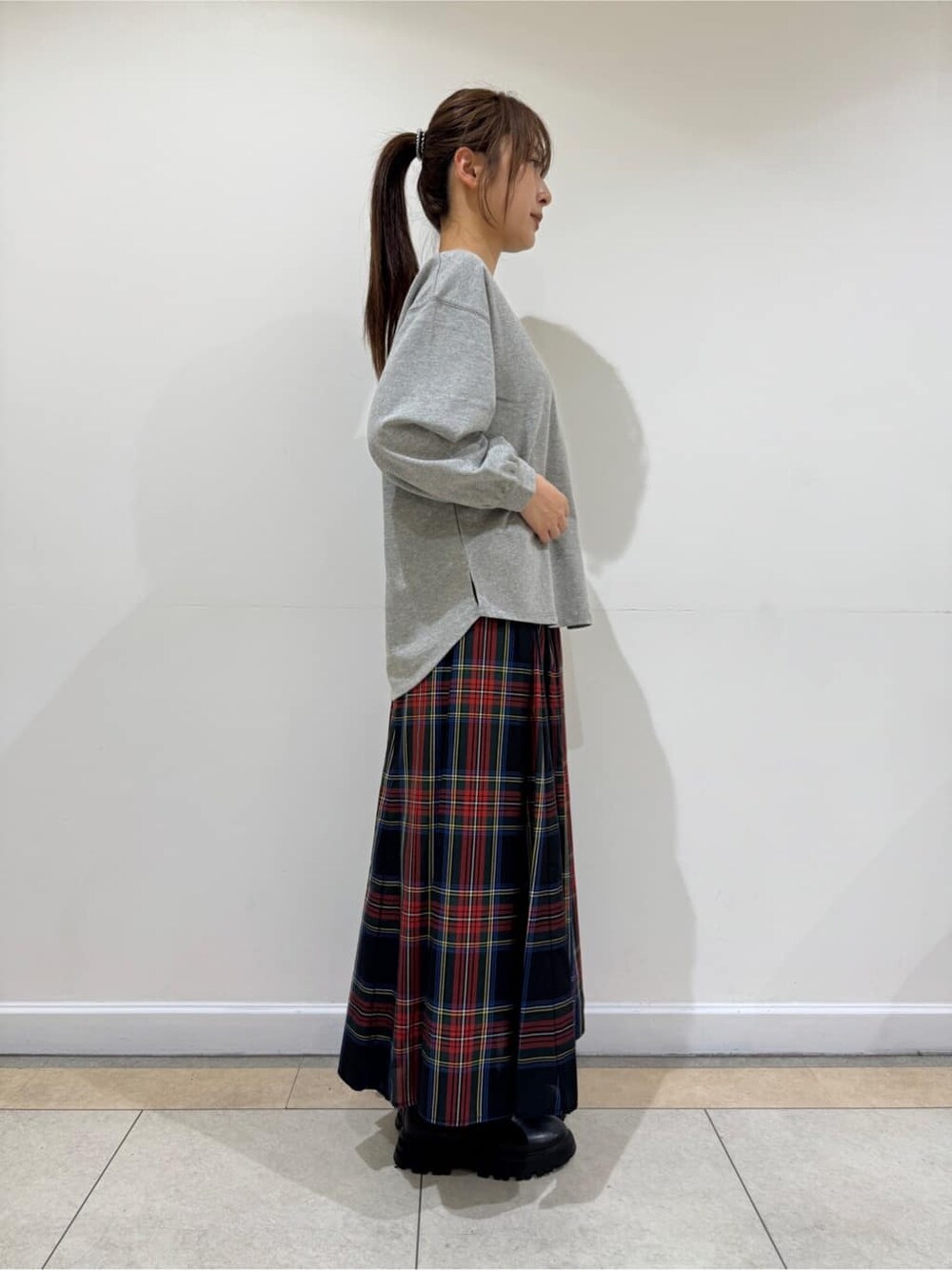 グレー系のTシャツ/カットソー、ブラック系のスカート、ブラック系のブーツを着用したレディースの秋コーディネートの3枚目の写真