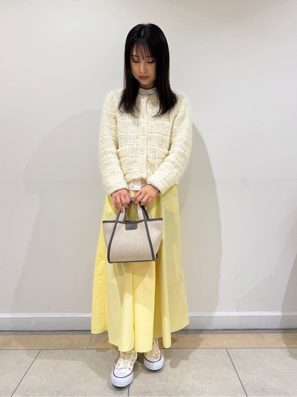 ホワイト系のカーディガン/ボレロ、ホワイト系のシャツ/ブラウス、イエロー系のスカートを着用したレディースの冬コーディネートの2枚目の写真