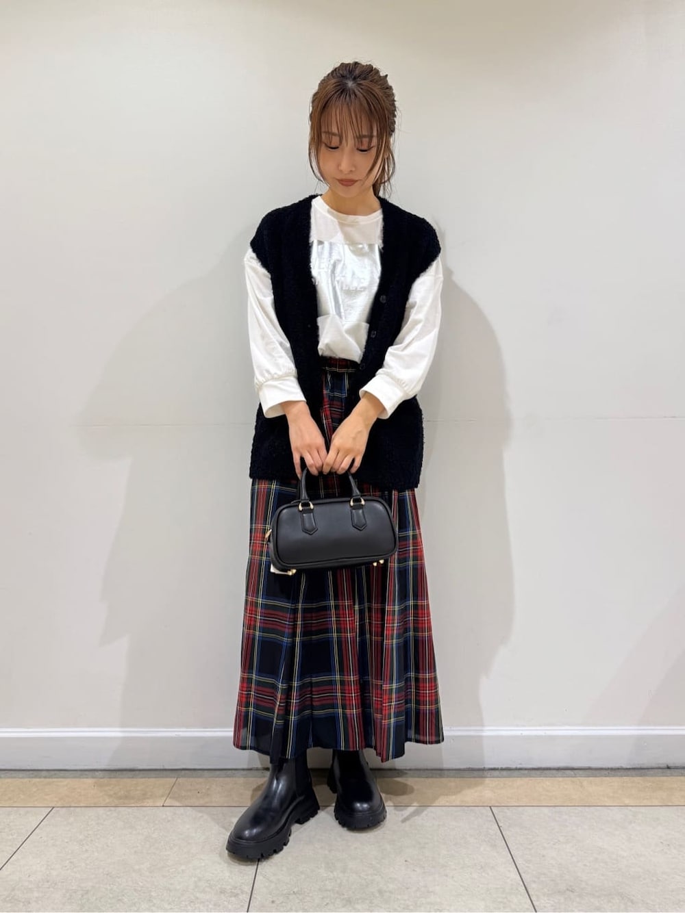 ホワイト系のTシャツ/カットソー、ブルー系のベスト、ブラック系のスカートを着用したレディースの秋コーディネートの2枚目の写真