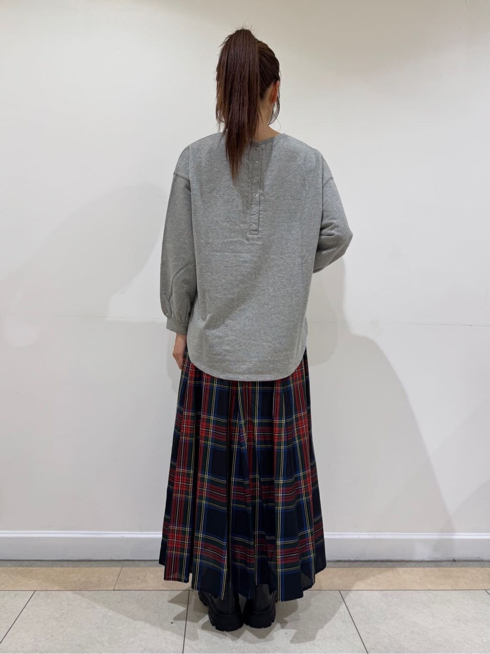 グレー系のTシャツ/カットソー、ブラック系のスカート、ブラック系のブーツを着用したレディースの秋コーディネートの4枚目の写真