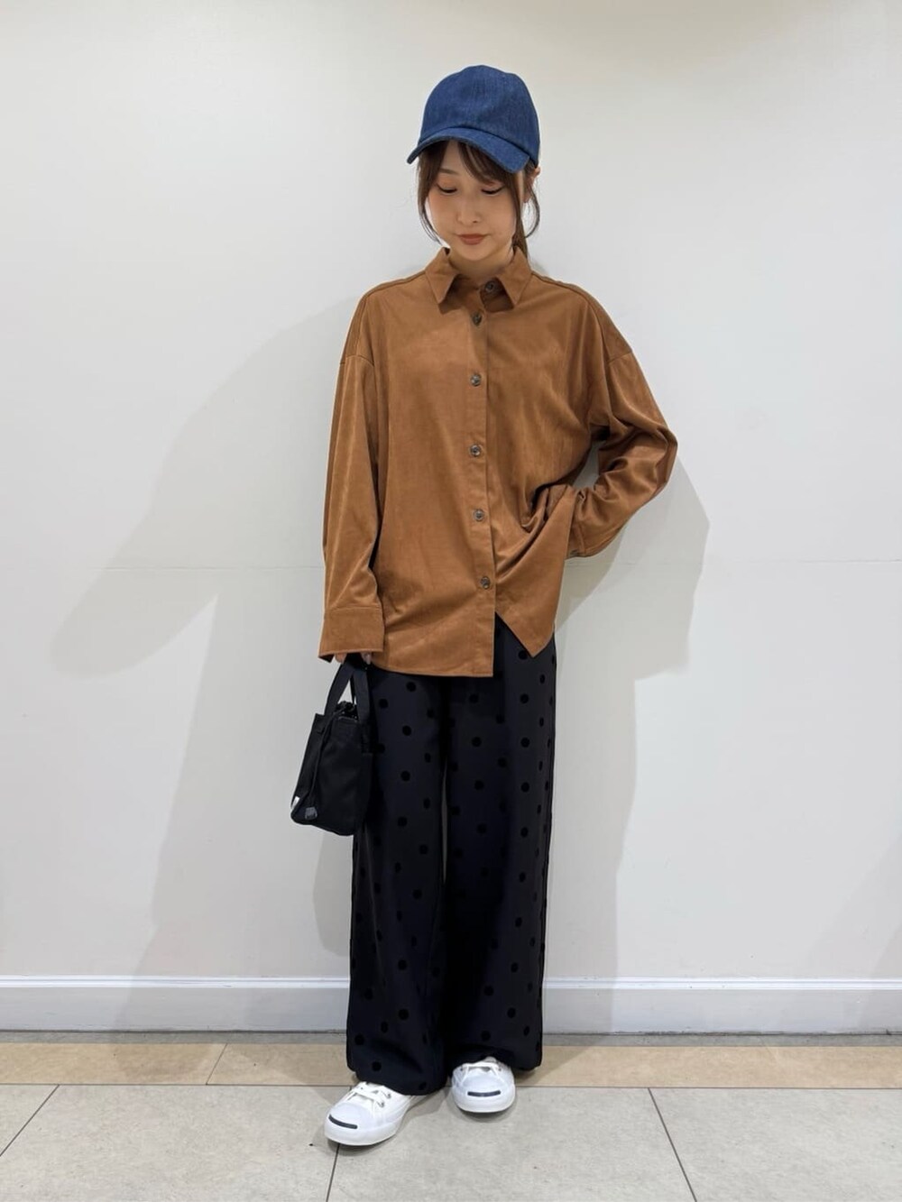 イエロー系のシャツ/ブラウス、ブラック系のその他パンツ、ブルー系のキャップを着用したレディースの秋コーディネートの2枚目の写真