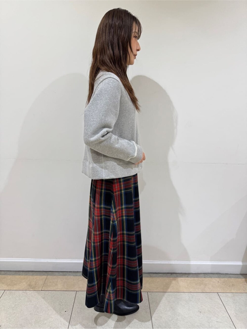 グレー系のカーディガン/ボレロ、レッド系のスカート、ブラック系のブーツを着用したレディースの冬コーディネートの3枚目の写真