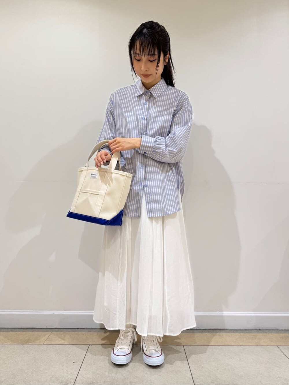 イエロー系のシャツ/ブラウス、ホワイト系のスカートを着用したレディースの夏コーディネートの2枚目の写真