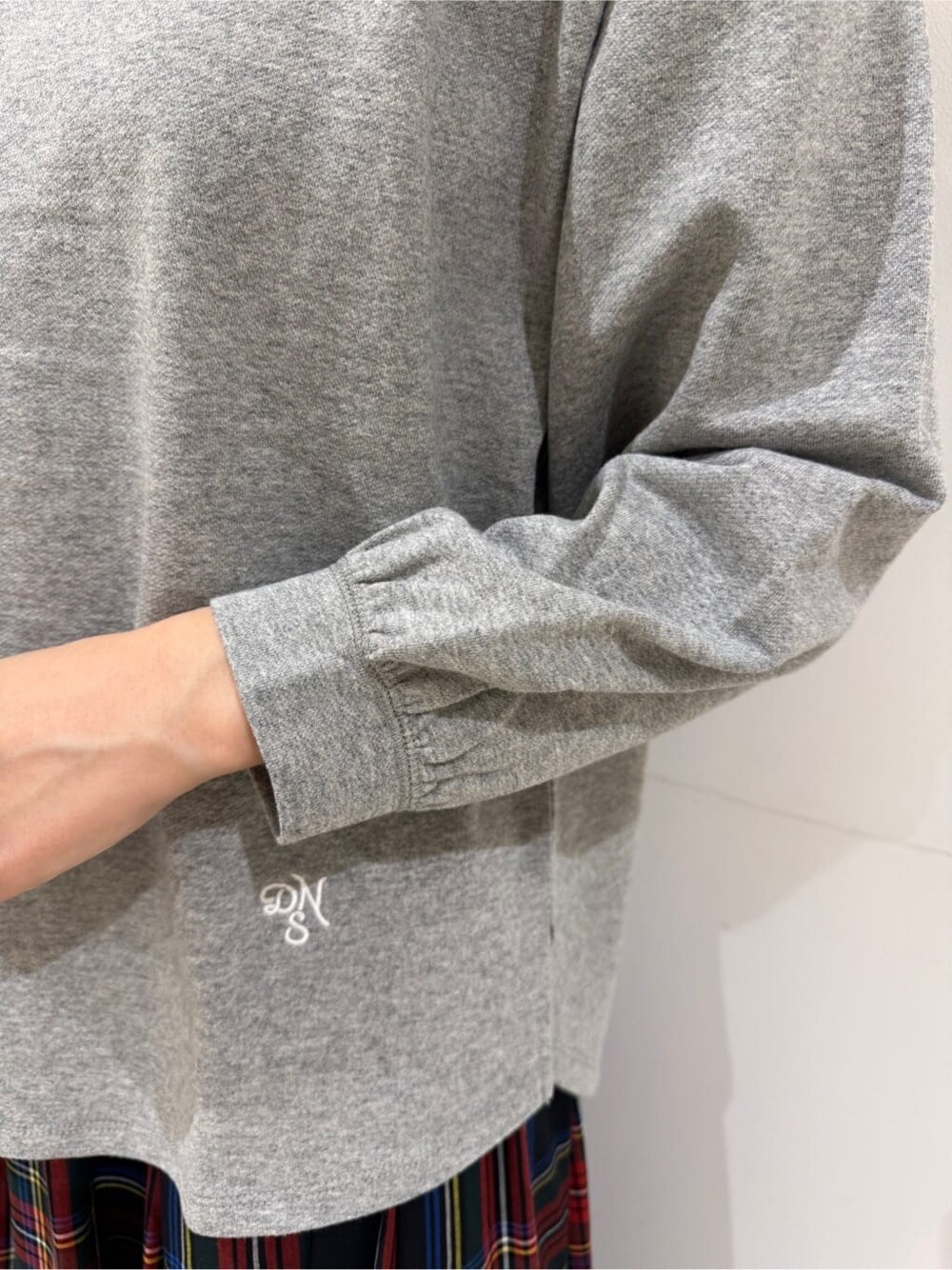 グレー系のTシャツ/カットソー、ブラック系のスカート、ブラック系のブーツを着用したレディースの秋コーディネートの5枚目の写真