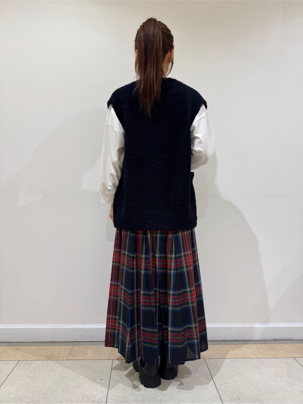 ホワイト系のTシャツ/カットソー、ブルー系のベスト、ブラック系のスカートを着用したレディースの秋コーディネートの4枚目の写真