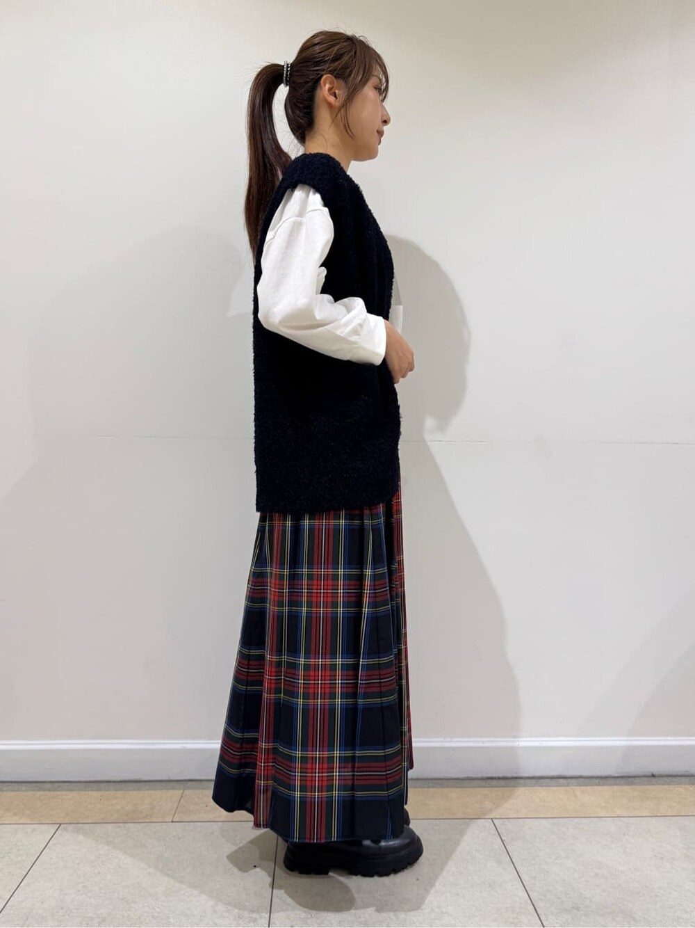 ホワイト系のTシャツ/カットソー、ブルー系のベスト、ブラック系のスカートを着用したレディースの秋コーディネートの3枚目の写真