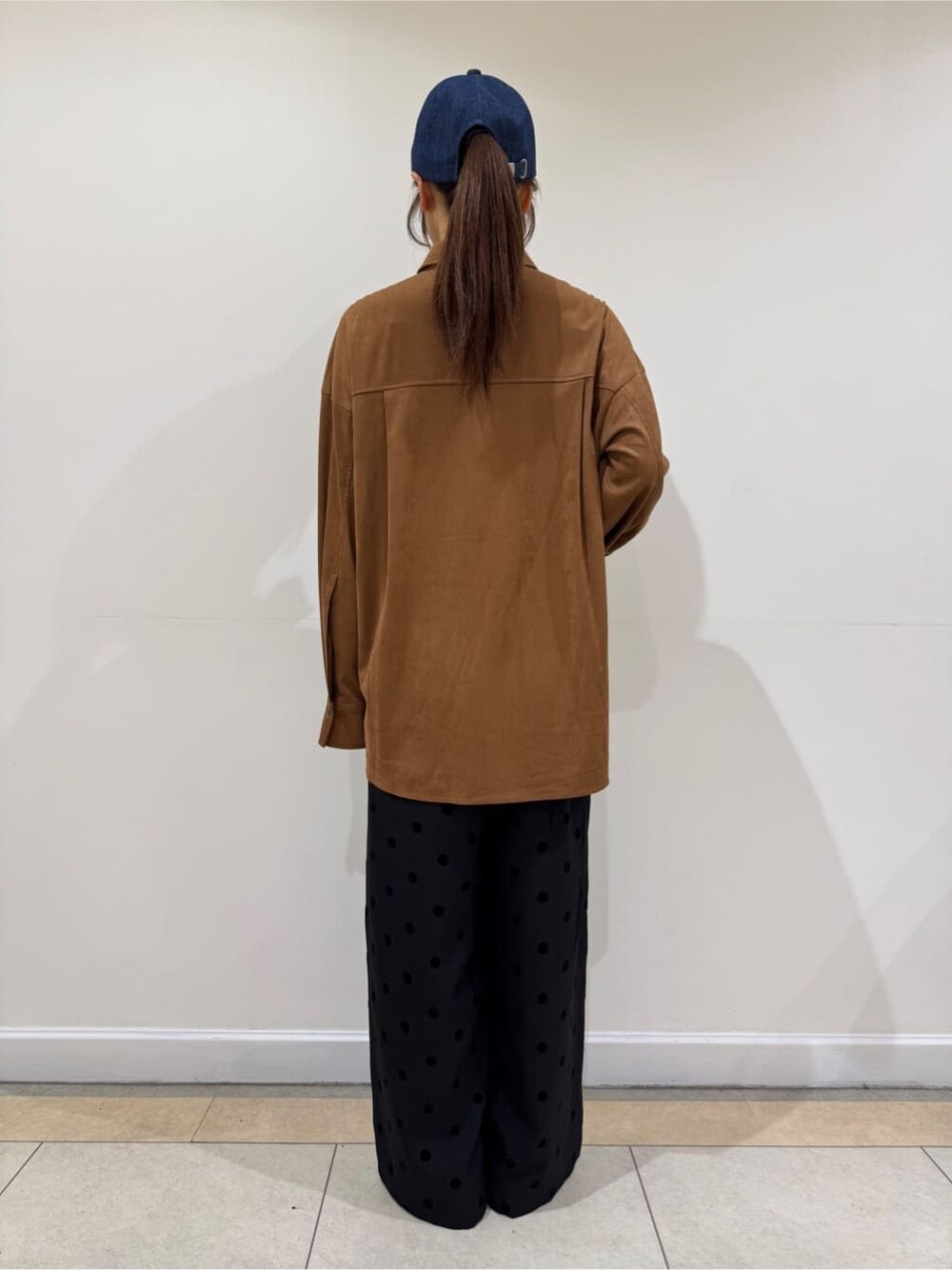 イエロー系のシャツ/ブラウス、ブラック系のその他パンツ、ブルー系のキャップを着用したレディースの秋コーディネートの4枚目の写真
