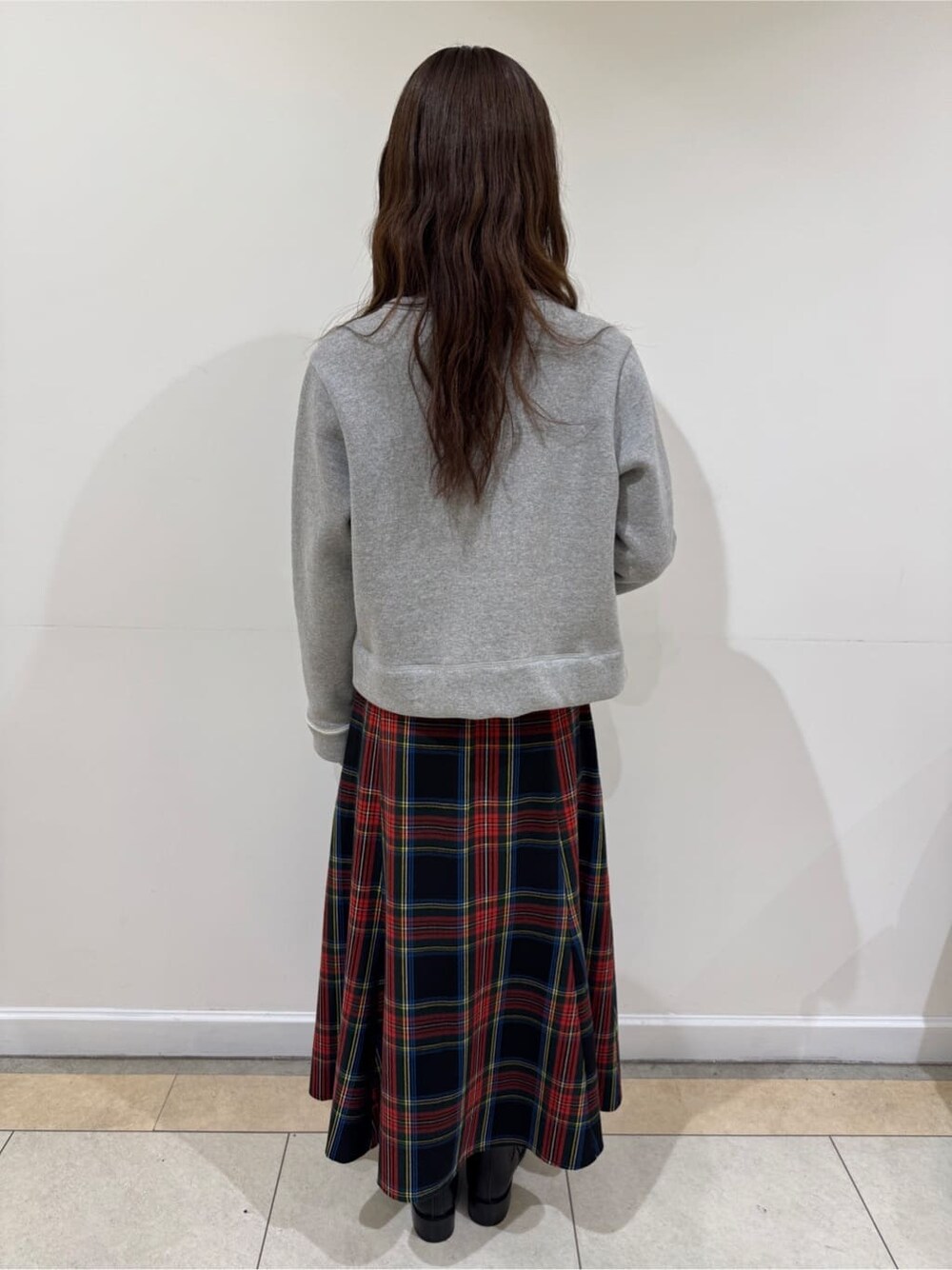 グレー系のカーディガン/ボレロ、レッド系のスカート、ブラック系のブーツを着用したレディースの冬コーディネートの4枚目の写真