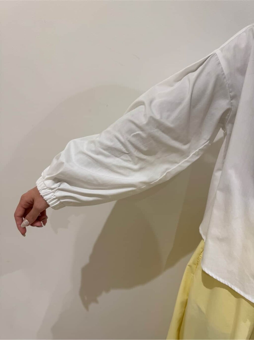 ホワイト系のカーディガン/ボレロ、ホワイト系のシャツ/ブラウス、イエロー系のスカートを着用したレディースの冬コーディネートの6枚目の写真