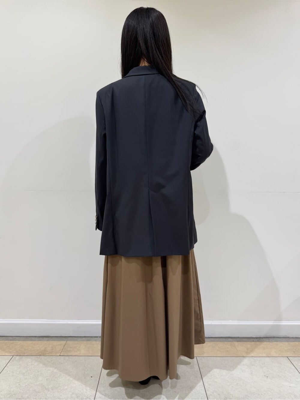 グレー系のテーラードジャケット、ブルー系のTシャツ/カットソー、ブラウン系のスカートを着用したレディースの春コーディネートの4枚目の写真