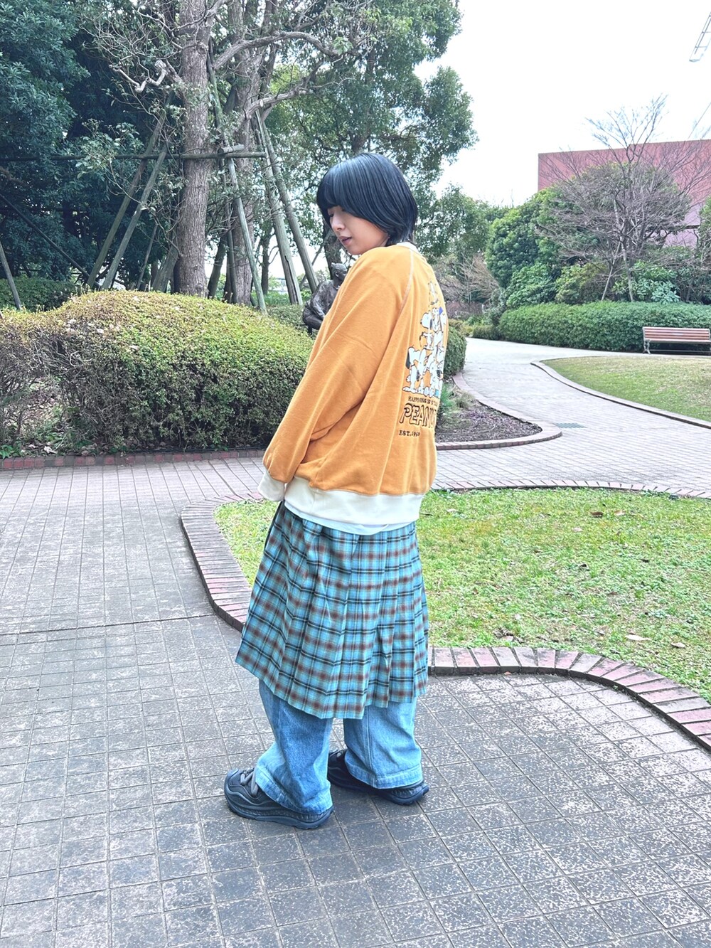 オレンジ系のスウェット、ブルー系のスカートを着用したレディースの冬コーディネートの2枚目の写真