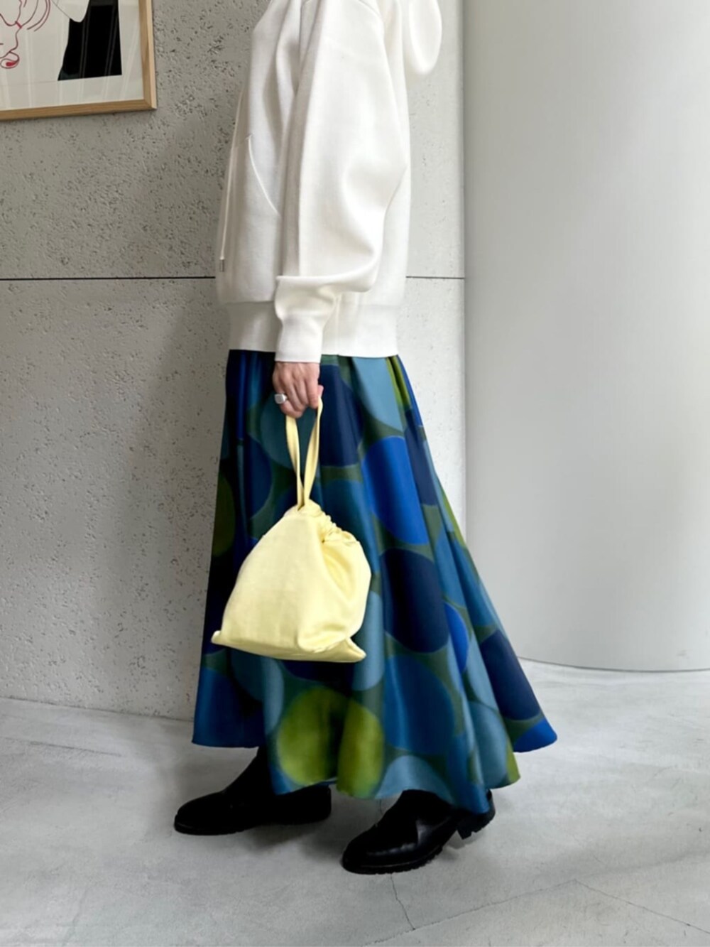 イエロー系のショルダーバッグ、ホワイト系のニット/セーター、ブルー系のスカートを着用したレディースの秋コーディネートの5枚目の写真