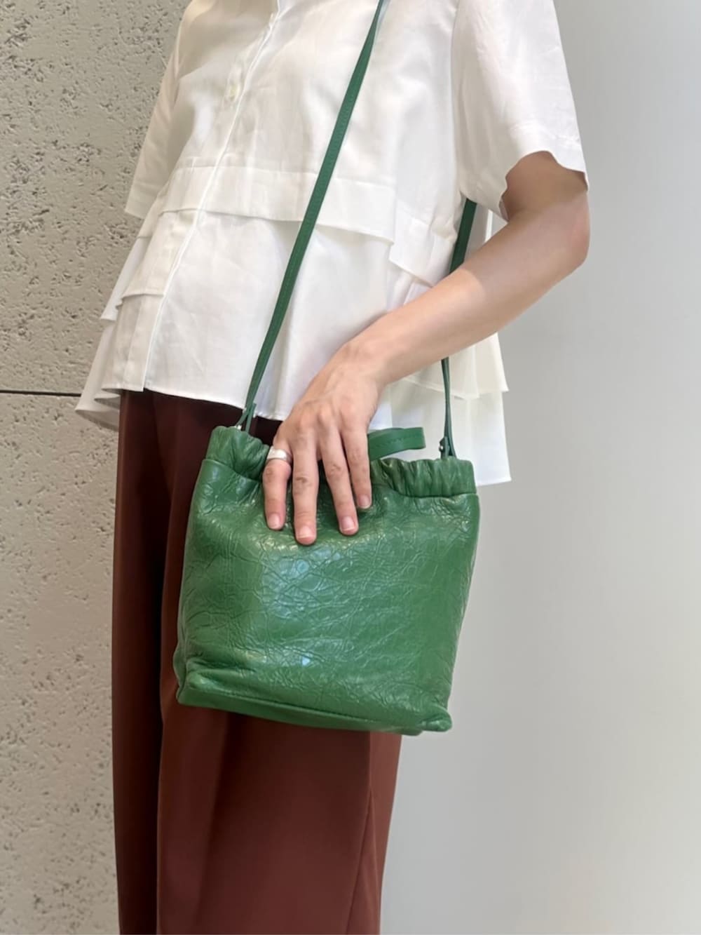 グリーン系のショルダーバッグ、ブラック系のサンダル、ホワイト系のシャツ/ブラウスを着用したレディースの夏コーディネートの2枚目の写真