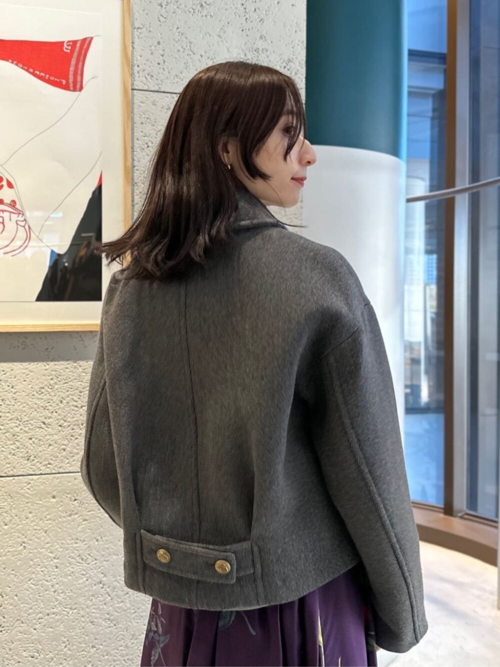 グレー系のブルゾン、グレー系のニット/セーター、パープル系のスカートを着用したレディースの冬コーディネートの4枚目の写真