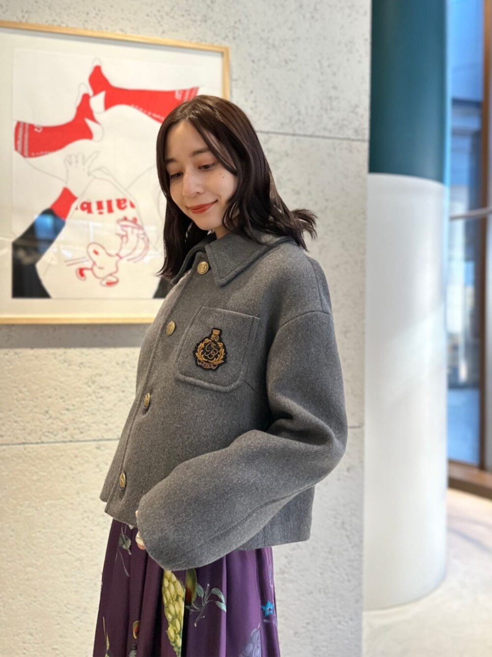 グレー系のブルゾン、グレー系のニット/セーター、パープル系のスカートを着用したレディースの冬コーディネートの2枚目の写真