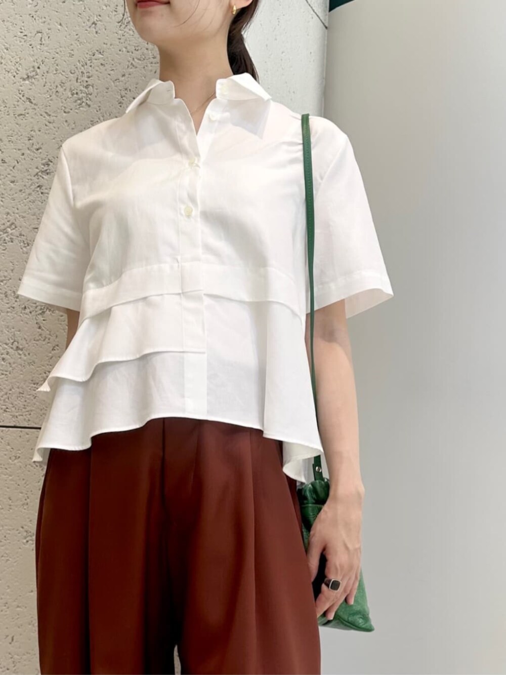 グリーン系のショルダーバッグ、ブラック系のサンダル、ホワイト系のシャツ/ブラウスを着用したレディースの夏コーディネートの3枚目の写真