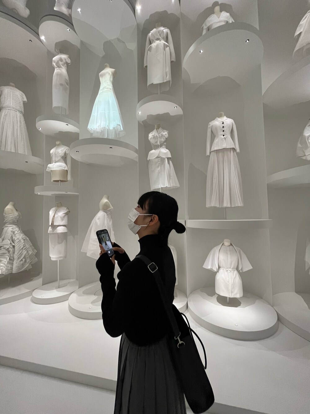 グレー系のスカート、ブラック系のトートバッグ、ブラック系のニット/セーターを着用したレディースの春コーディネートの2枚目の写真