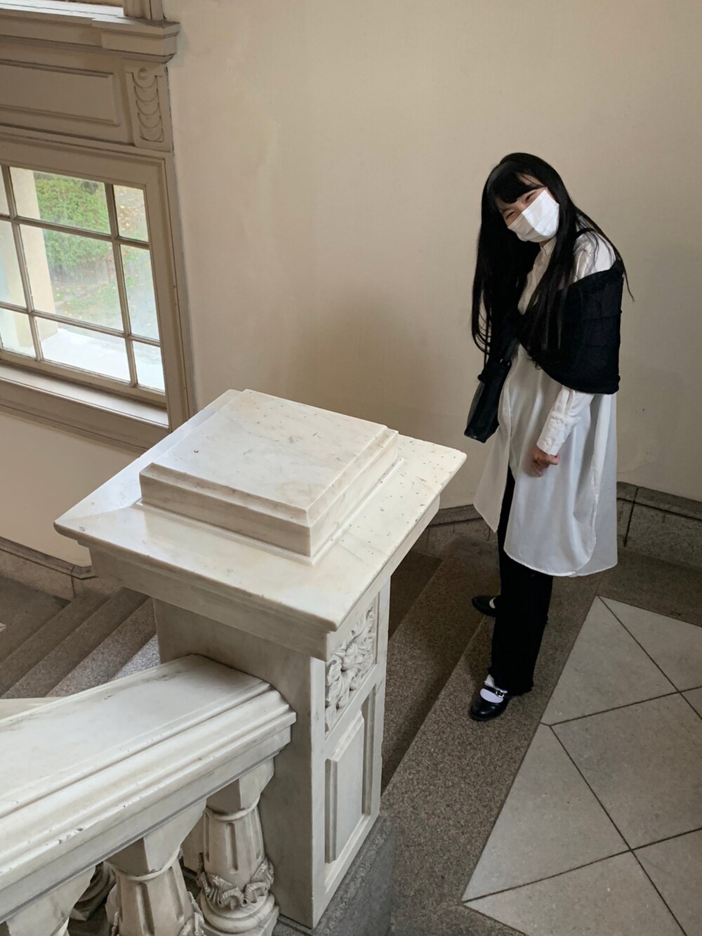 ブラック系のショルダーバッグ、ホワイト系のシャツワンピース、ブラック系のピアス（両耳用）を着用したレディースの春コーディネートの3枚目の写真