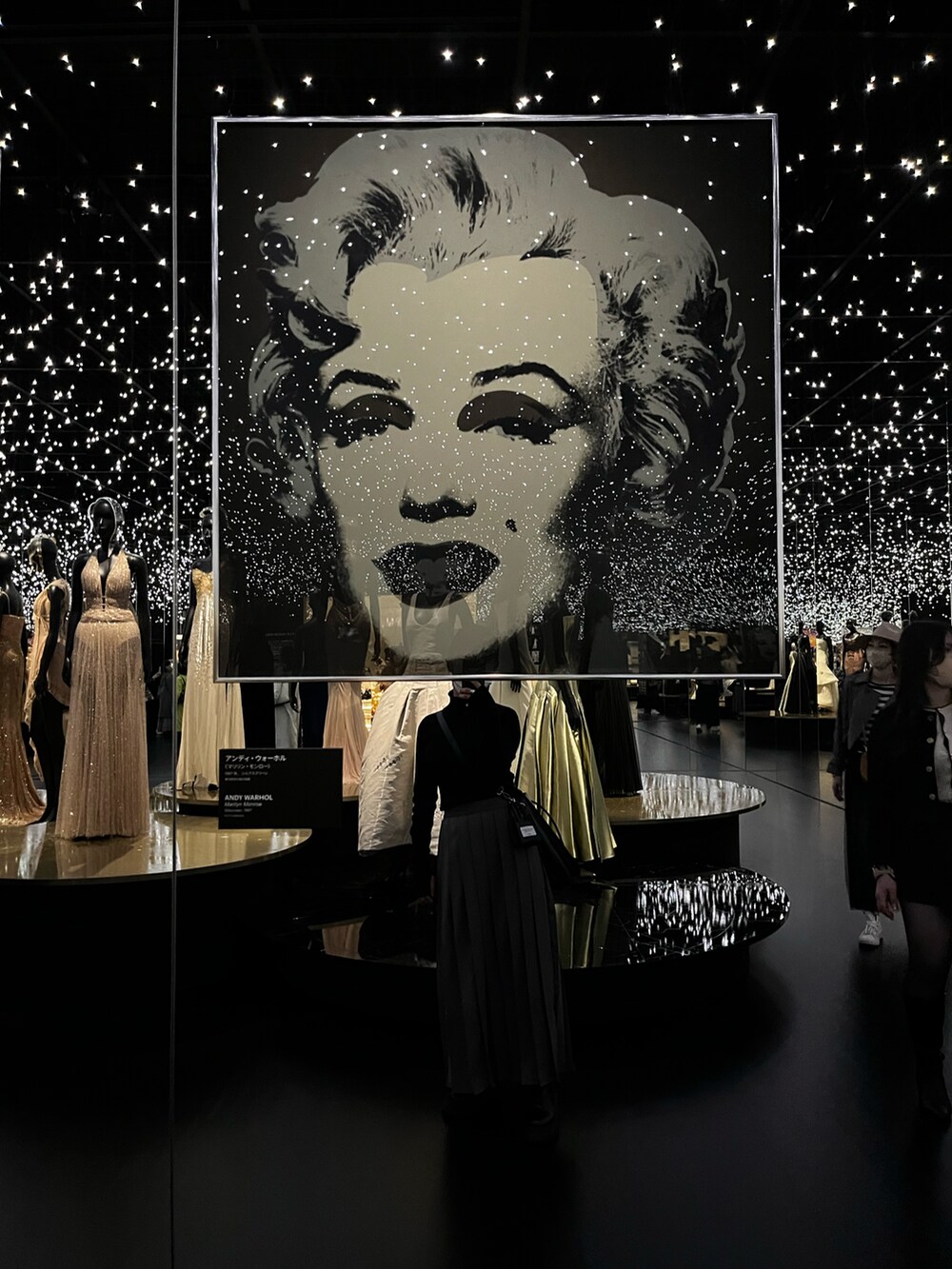 グレー系のスカート、ブラック系のトートバッグ、ブラック系のニット/セーターを着用したレディースの春コーディネートの3枚目の写真