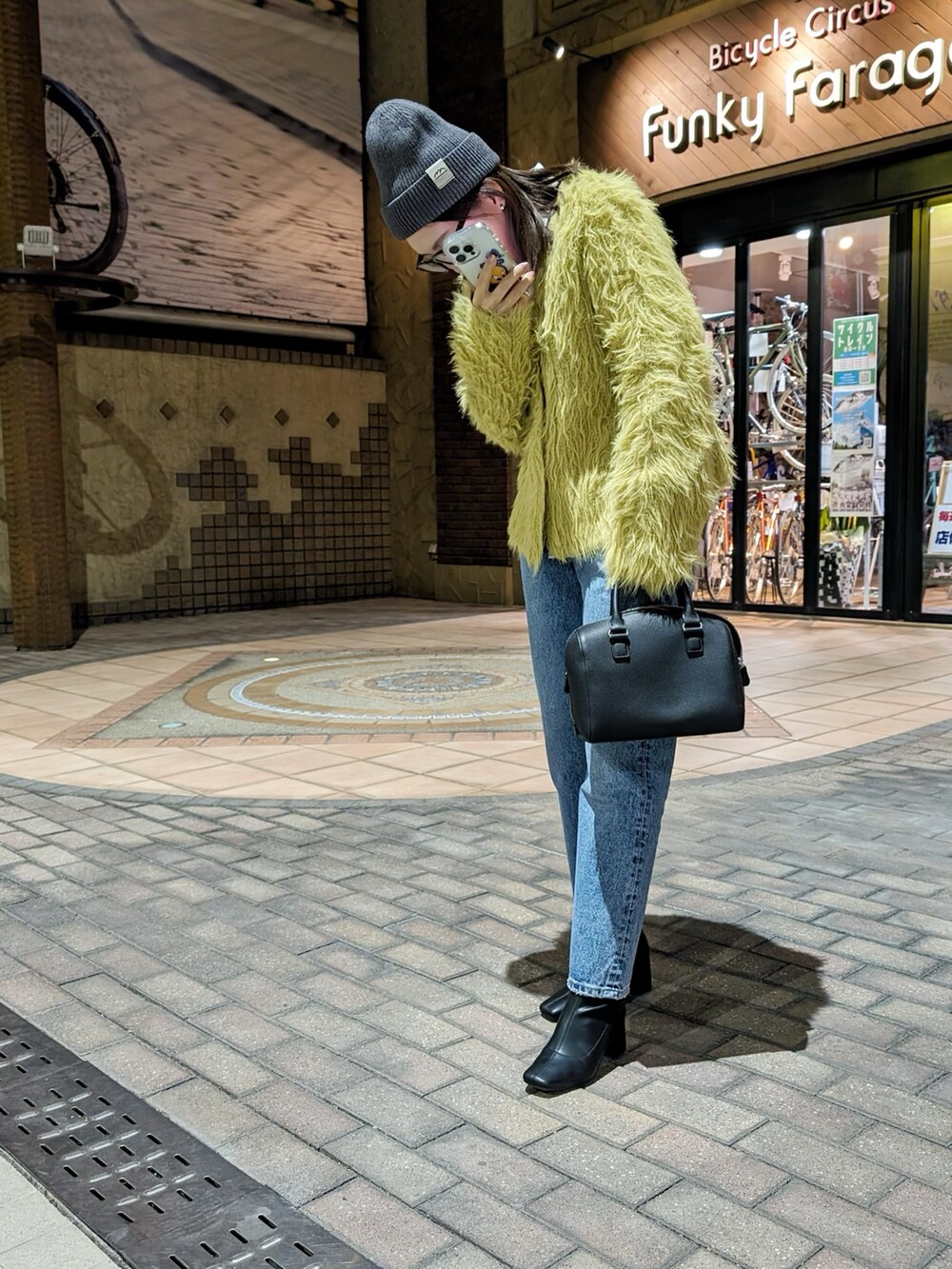 ブルー系のデニムパンツ、イエロー系のカーディガン/ボレロ、ブラック系のブーツを着用したレディースの冬コーディネートの2枚目の写真