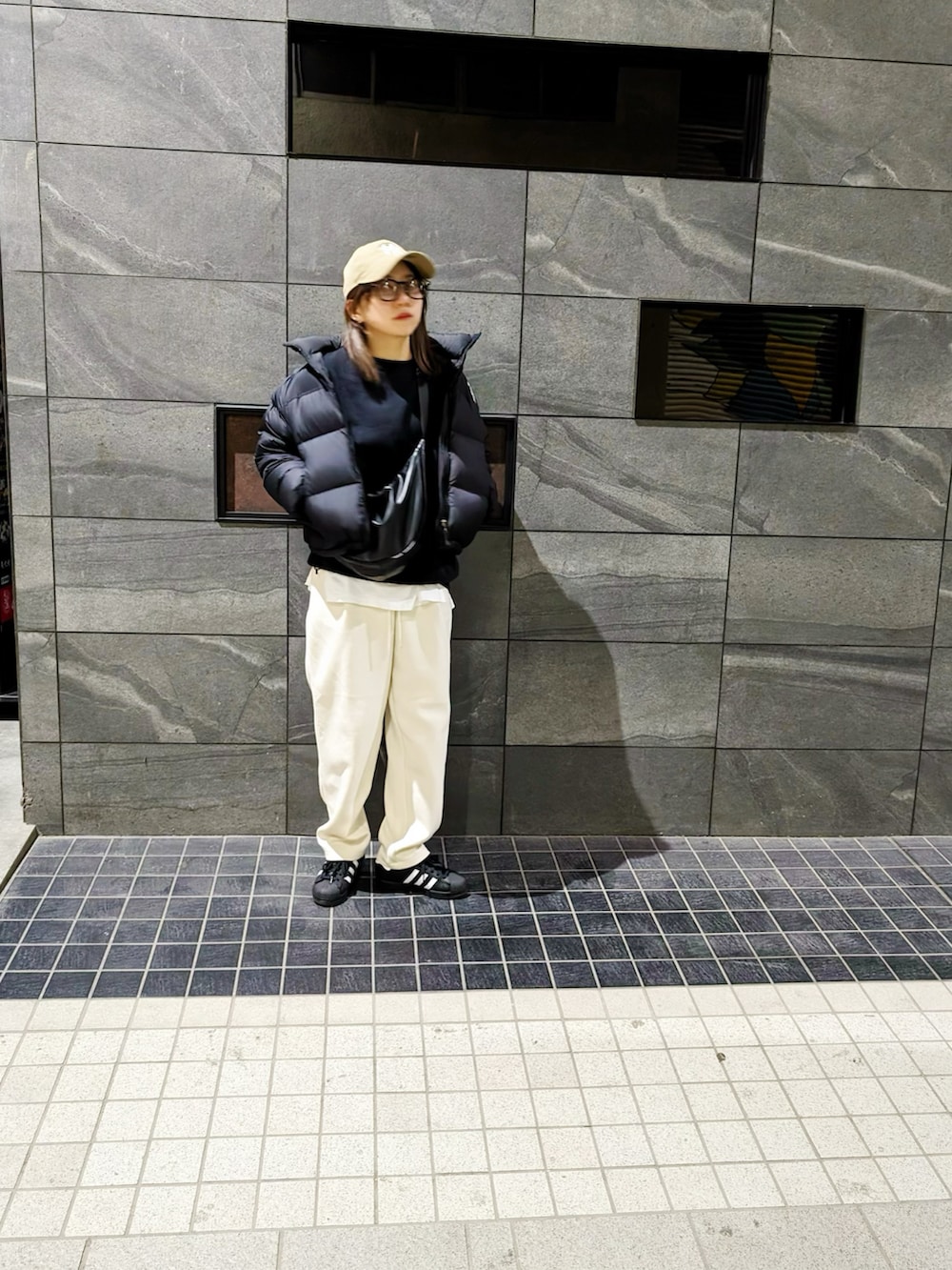 ホワイト系のスウェットパンツ、ブラック系のスニーカー、ブラック系のボディバッグ/ウエストポーチを着用したレディースの冬コーディネートの2枚目の写真