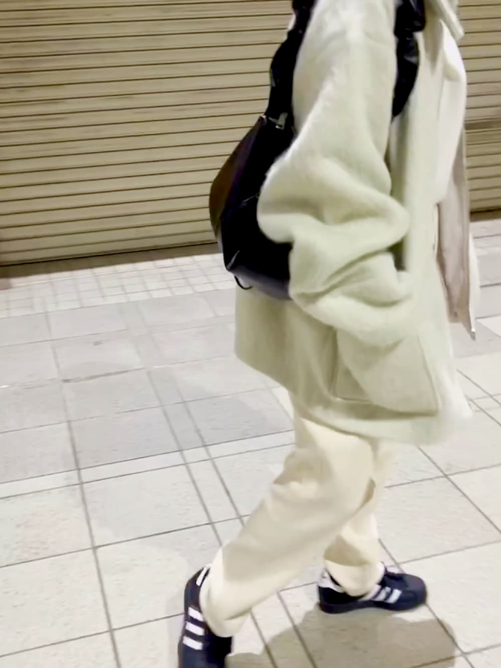 ブラック系のスニーカー、ホワイト系のスウェットパンツ、ホワイト系のニット/セーターを着用したレディースの冬コーディネートの3枚目の写真