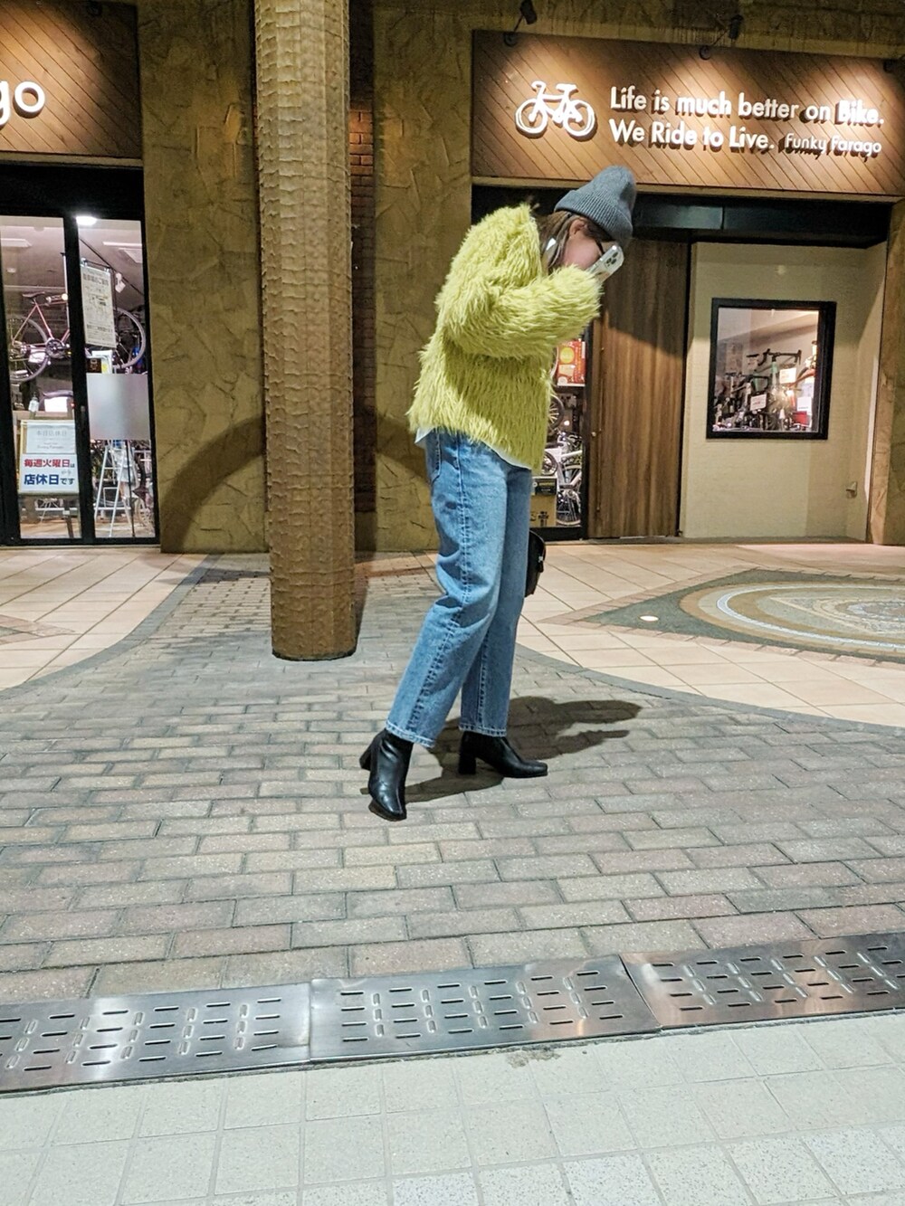 ブルー系のデニムパンツ、イエロー系のカーディガン/ボレロ、ブラック系のブーツを着用したレディースの冬コーディネートの3枚目の写真