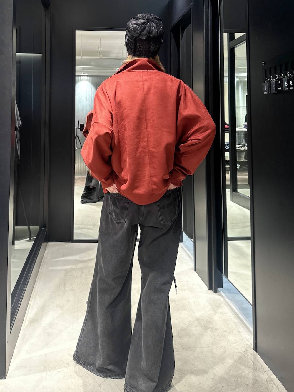 ブラック系のデニムパンツ、オレンジ系のスウェット、シルバー系のネックレスを着用したメンズの秋コーディネートの4枚目の写真