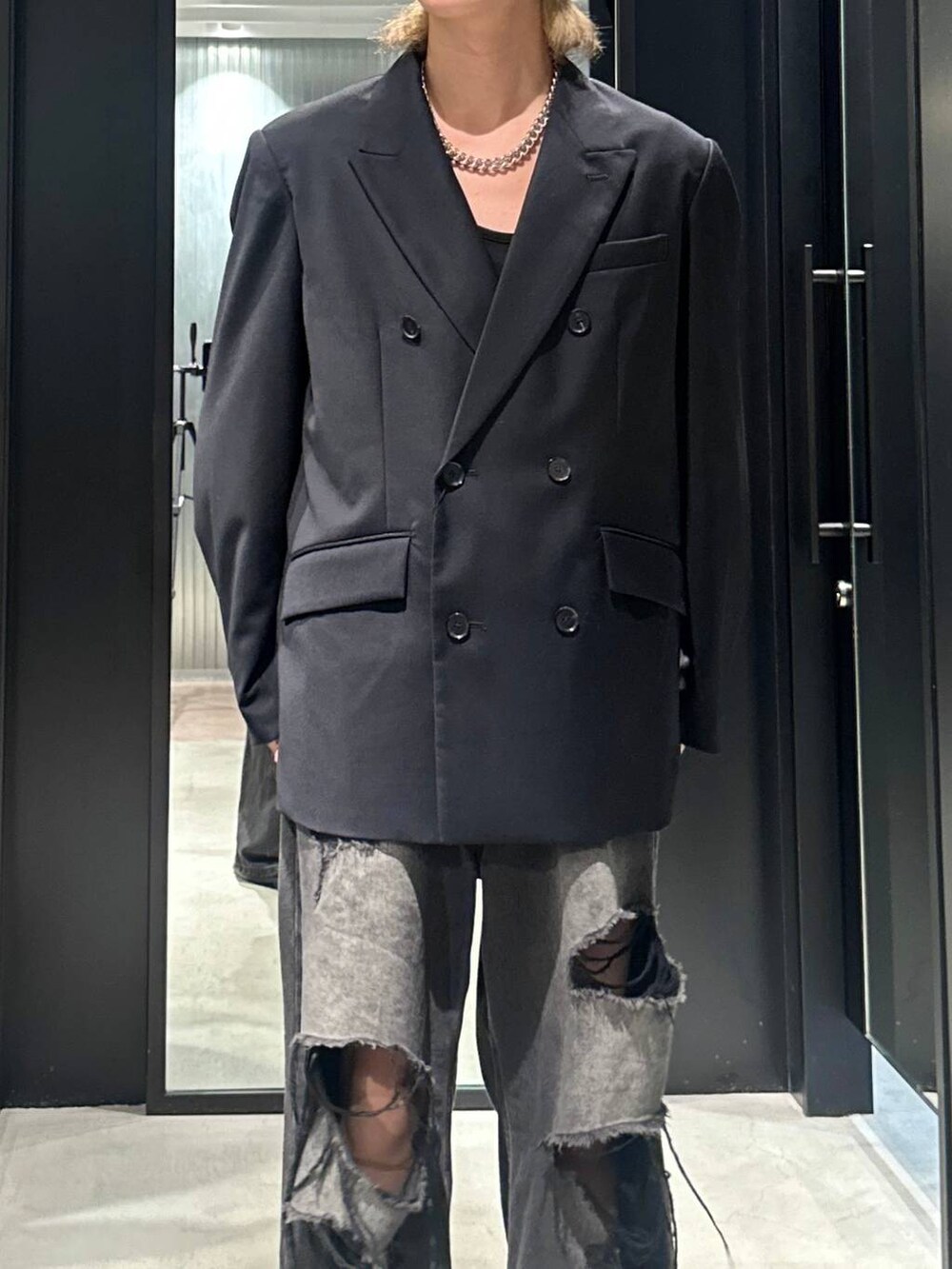 ブラック系のデニムパンツ、ブラック系のテーラードジャケット、シルバー系のネックレスを着用したメンズの秋コーディネートの2枚目の写真