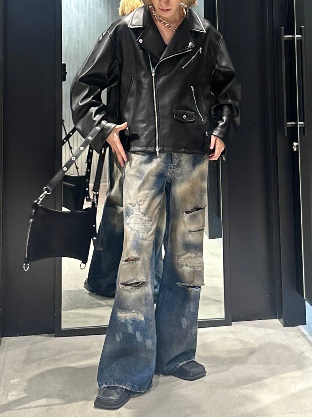 ブラック系のショルダーバッグ、ブラック系のライダースジャケット、ブルー系のデニムパンツを着用したメンズの秋コーディネートの5枚目の写真