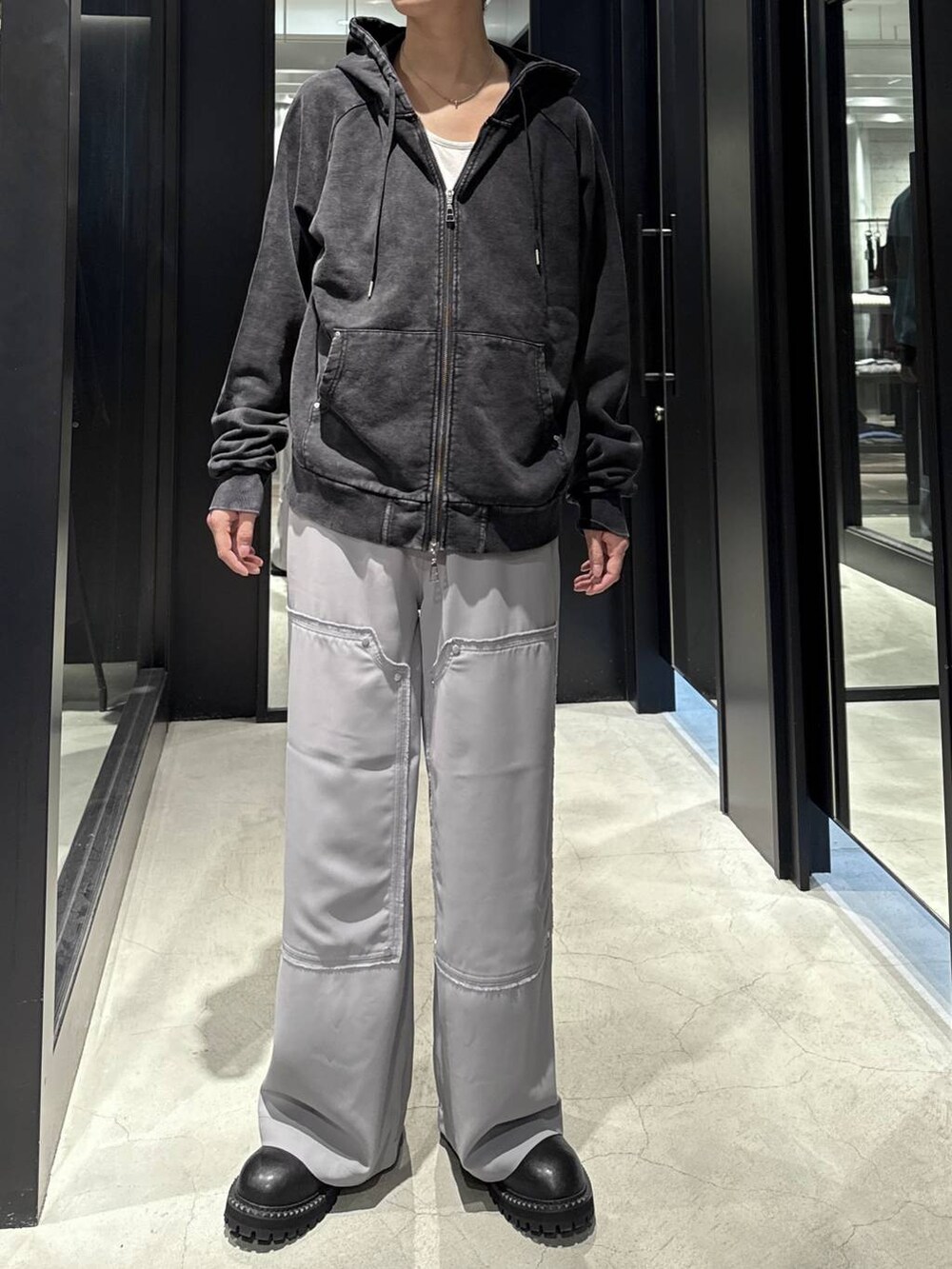 ブラック系のパーカー、ブラック系のブーツ、シルバー系のネックレスを着用したメンズの秋コーディネートの4枚目の写真