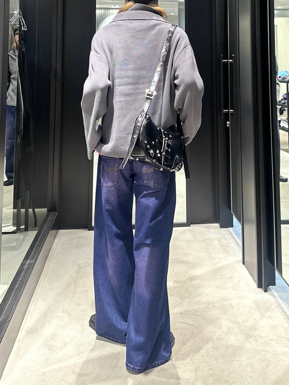 パープル系のデニムパンツ、グレー系のニット/セーター、ブラック系のショルダーバッグを着用したメンズの秋コーディネートの4枚目の写真