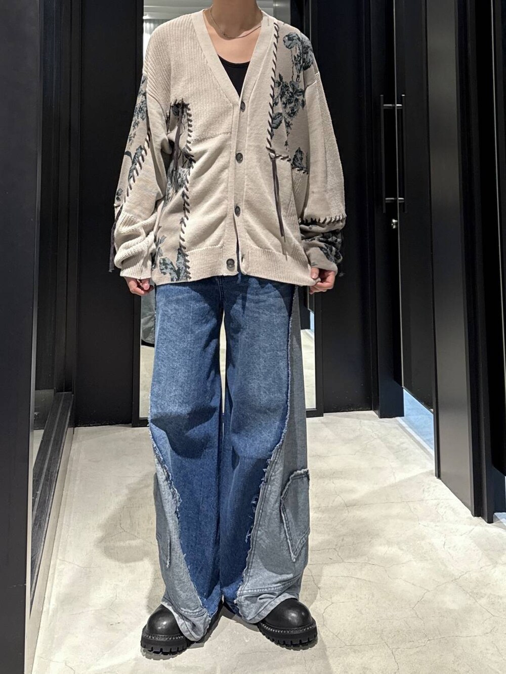 ブラック系のタンクトップ、ブルー系のデニムパンツ、グレー系のカーディガン/ボレロを着用したメンズの秋コーディネートの4枚目の写真