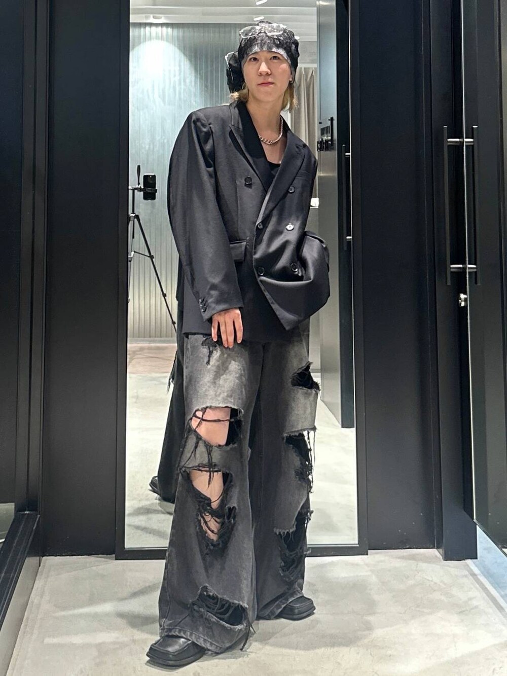 ブラック系のデニムパンツ、ブラック系のテーラードジャケット、シルバー系のネックレスを着用したメンズの秋コーディネートの5枚目の写真