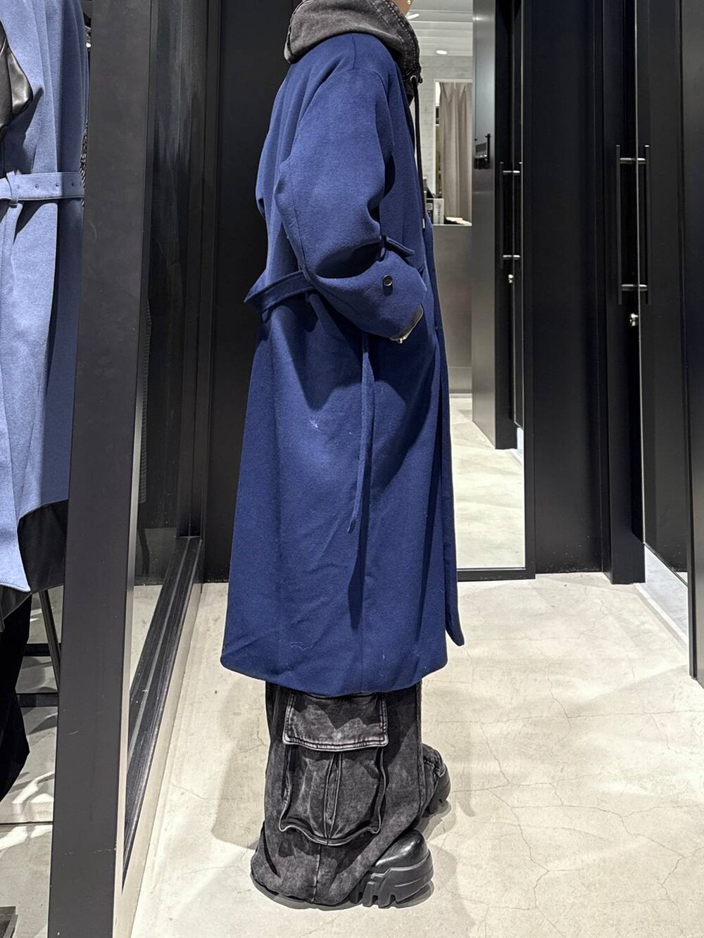 ブルー系のチェスターコート、ブラック系のパーカー、ブラック系のスウェットパンツを着用したメンズの冬コーディネートの2枚目の写真